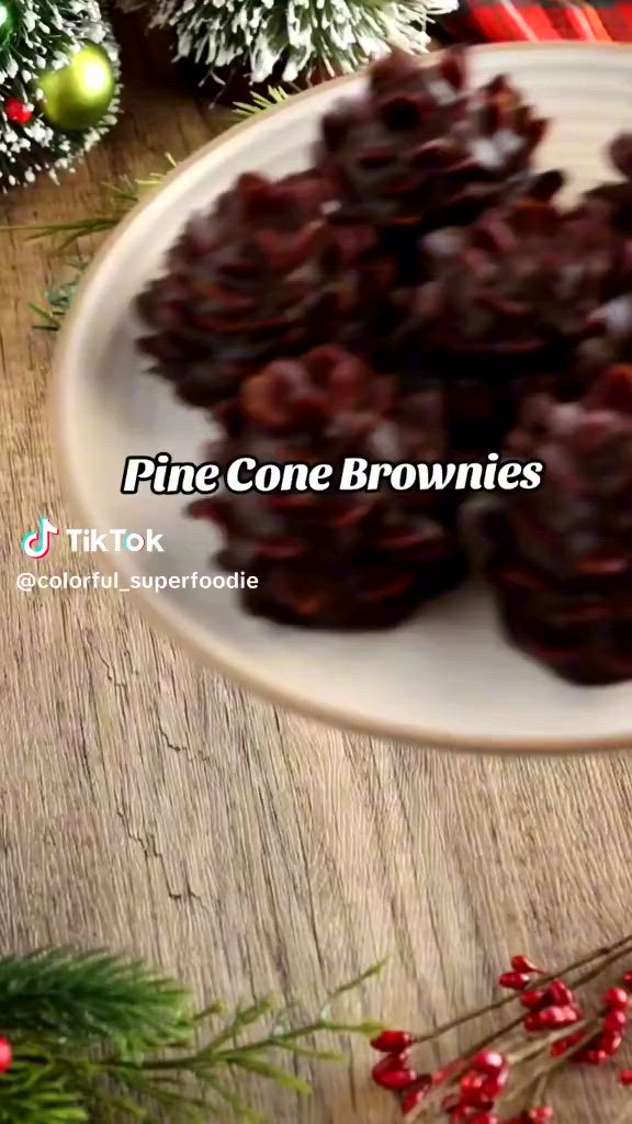 This may contain: pine cone brownies on a white plate with christmas decorations in the backgroud