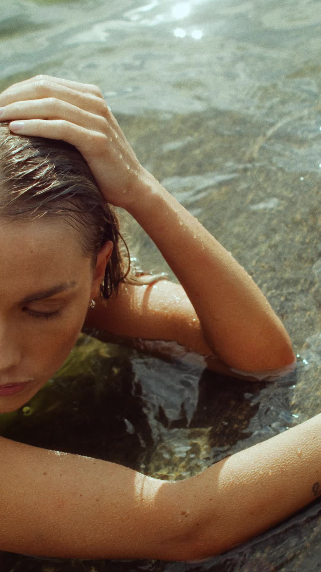 This may contain: a woman in the water with her hands on her head