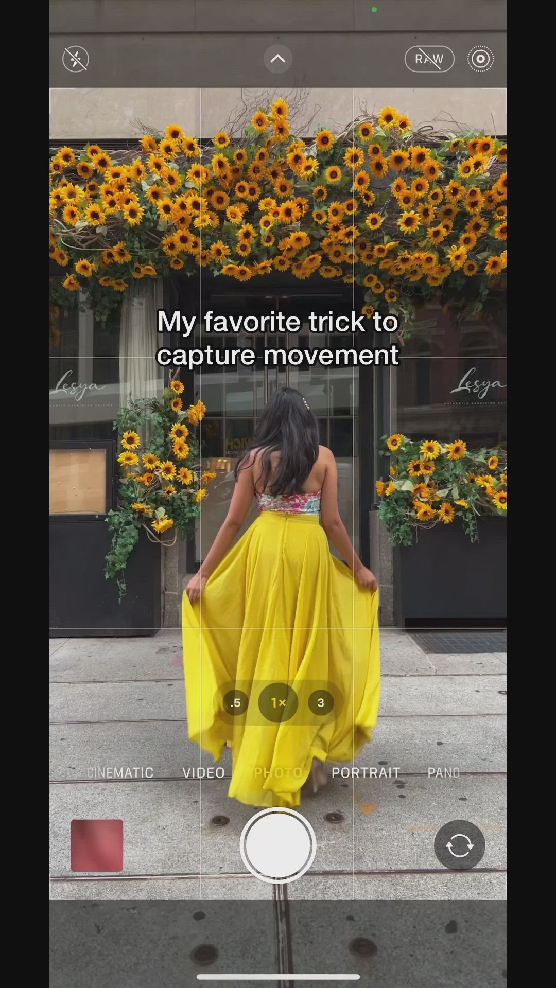 This may contain: a woman in a yellow dress walking down the street with sunflowers behind her