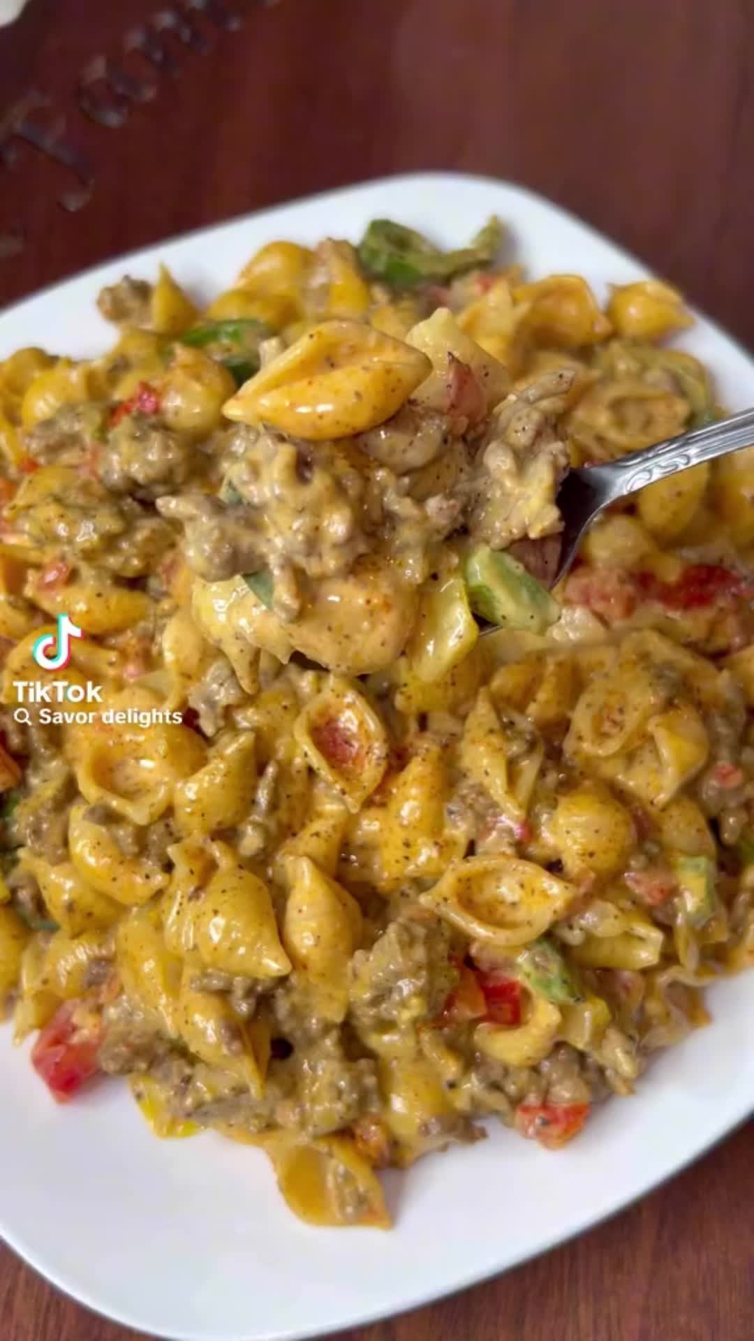 This may contain: a white plate topped with macaroni and cheese on top of a wooden table