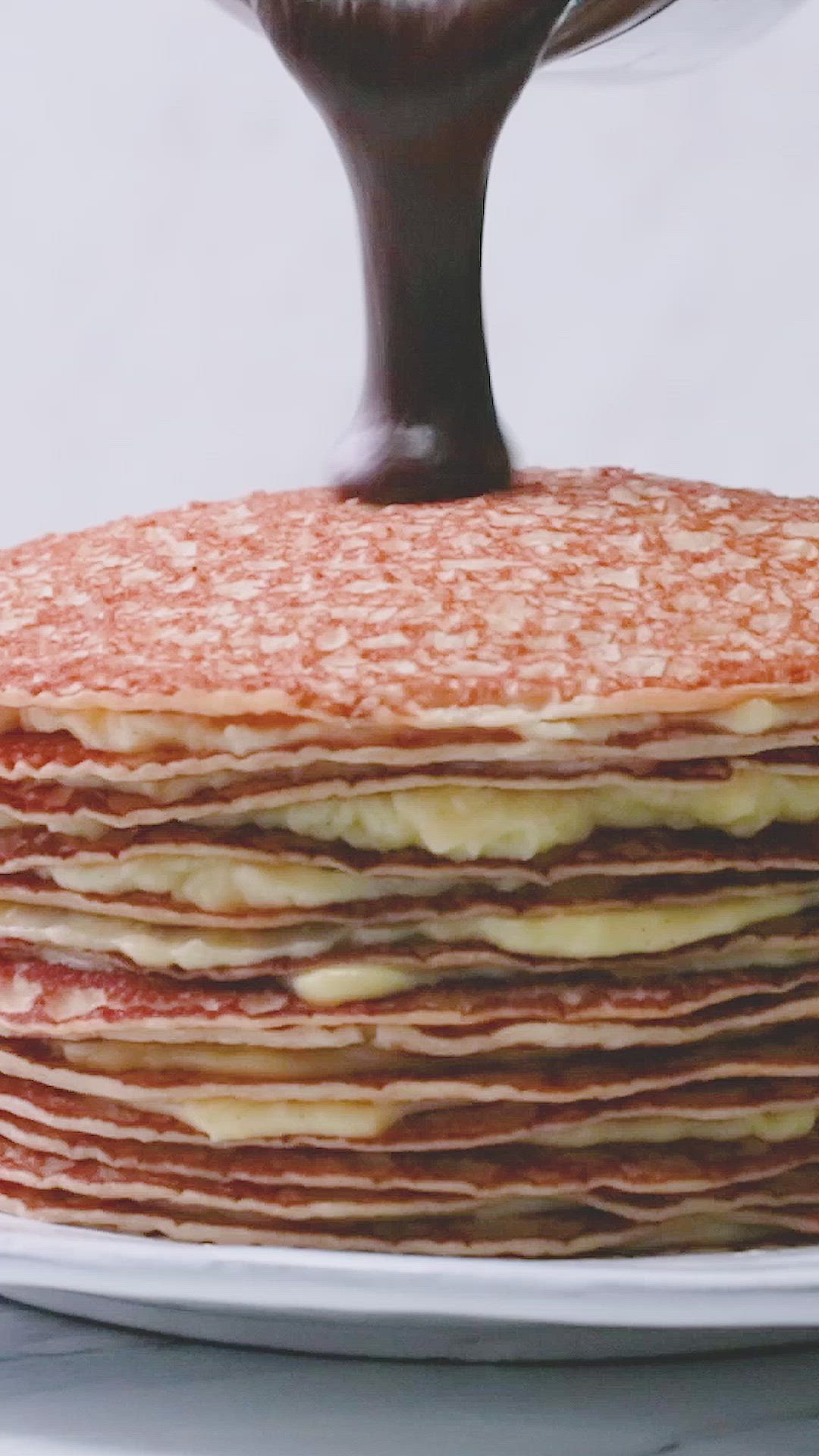 This may contain: a stack of pancakes covered in chocolate syrup