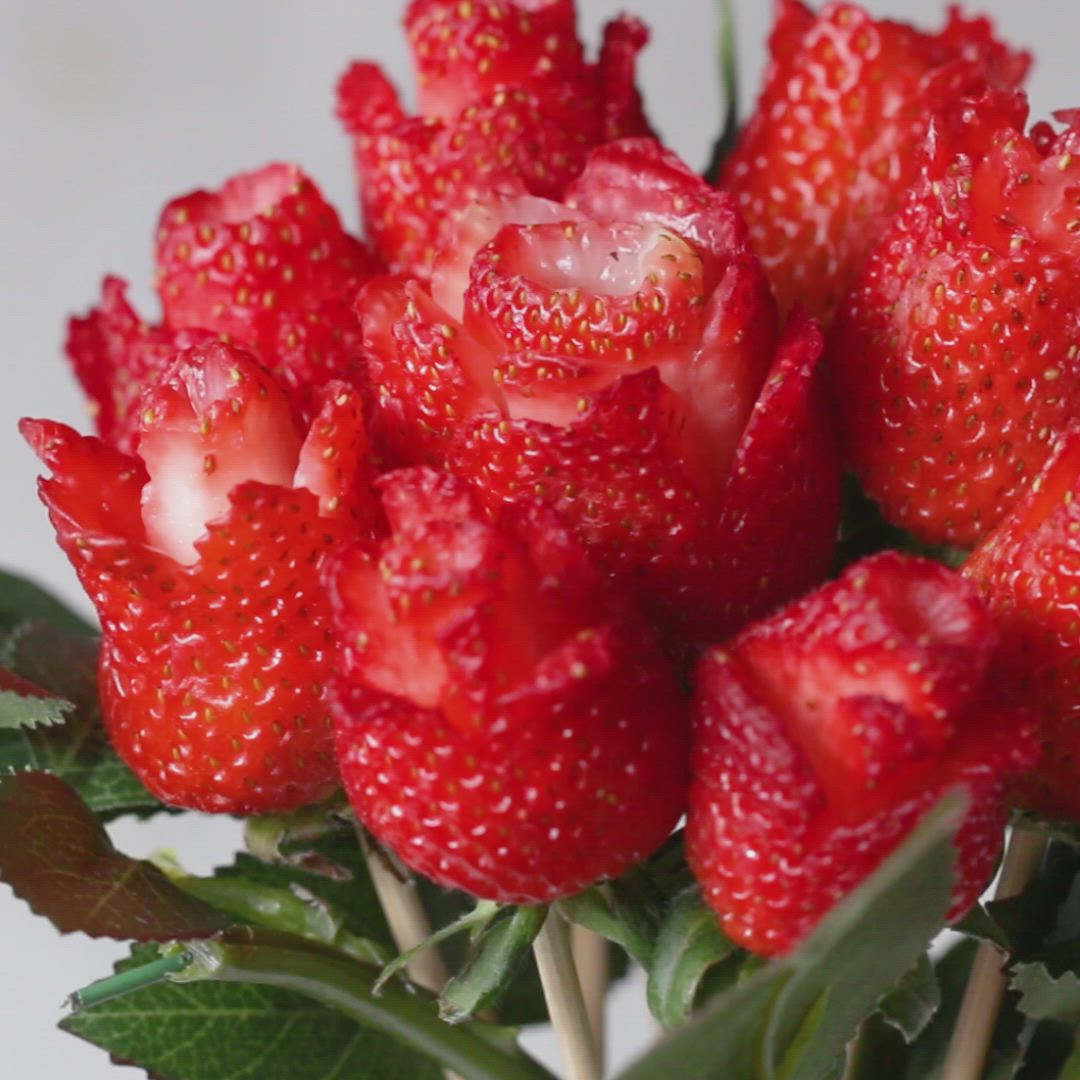 This may contain: a bunch of red strawberries sitting on top of each other in a glass vase