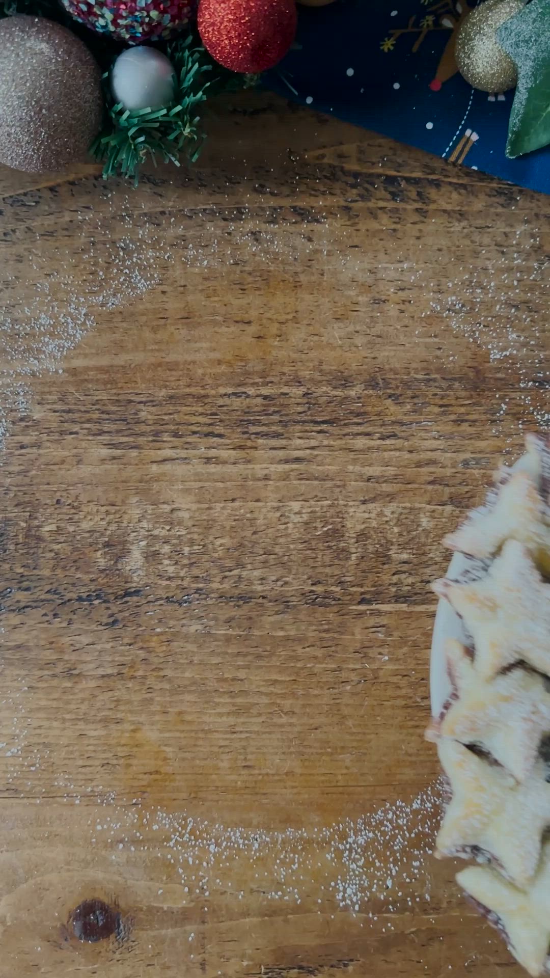 This may contain: a christmas wreath made out of star shaped cookies on top of a wooden table next to other holiday decorations