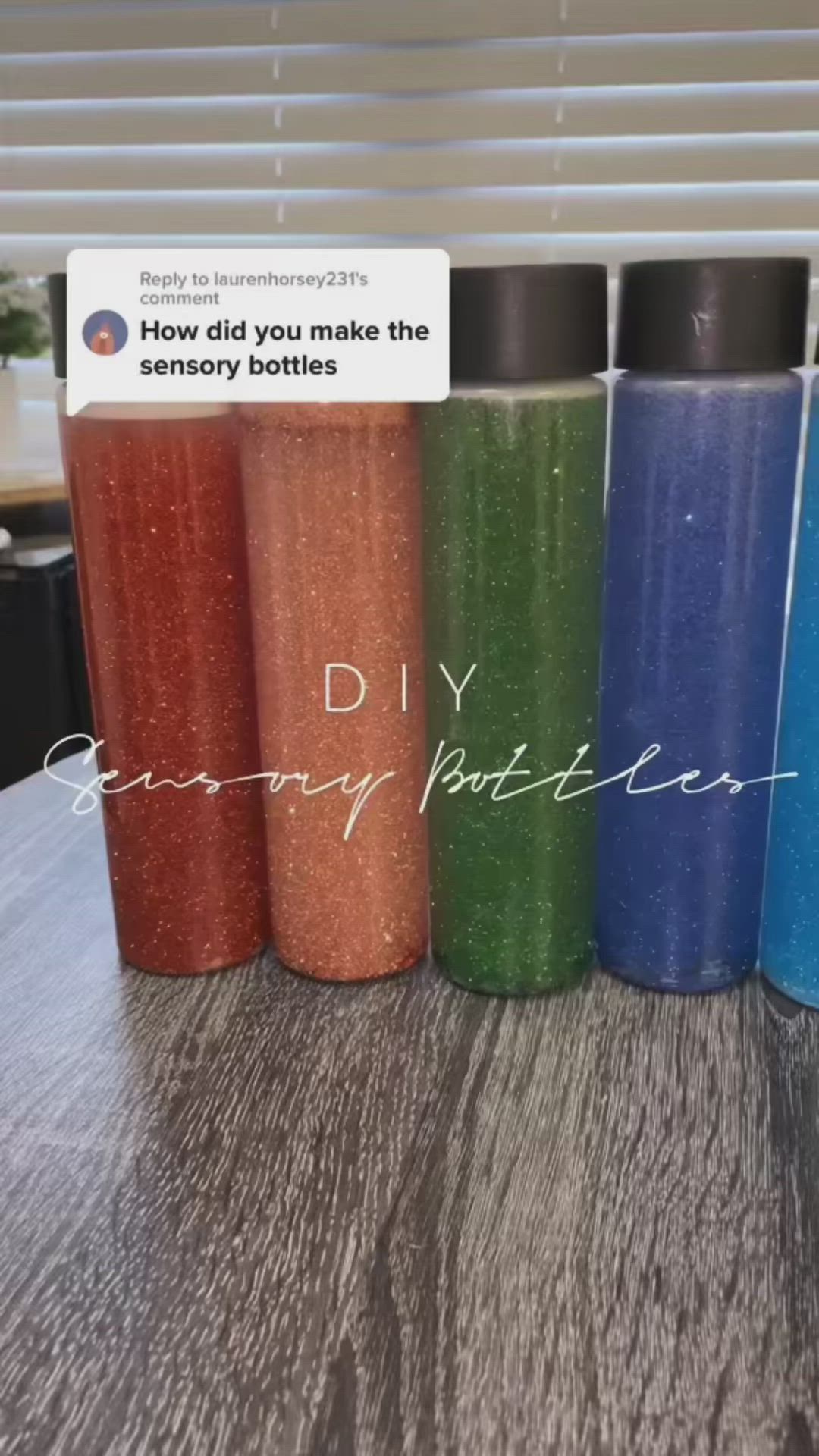 This may contain: a row of different colored water bottles sitting next to each other on a wooden table