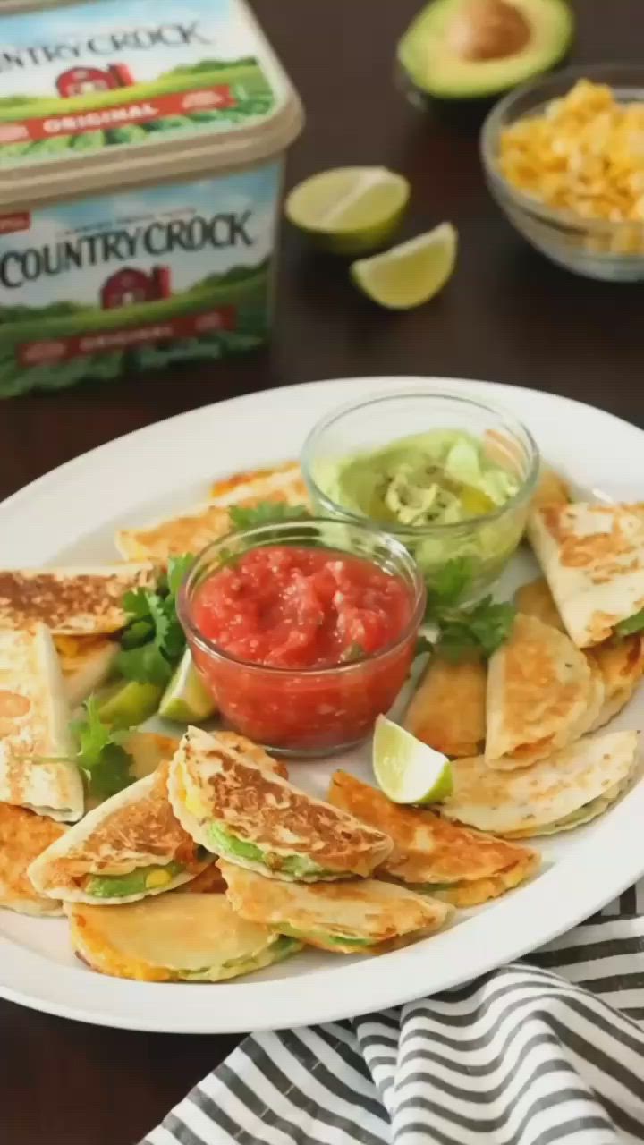 This may contain: a white plate topped with quesadillas and guacamole next to a container of salsa