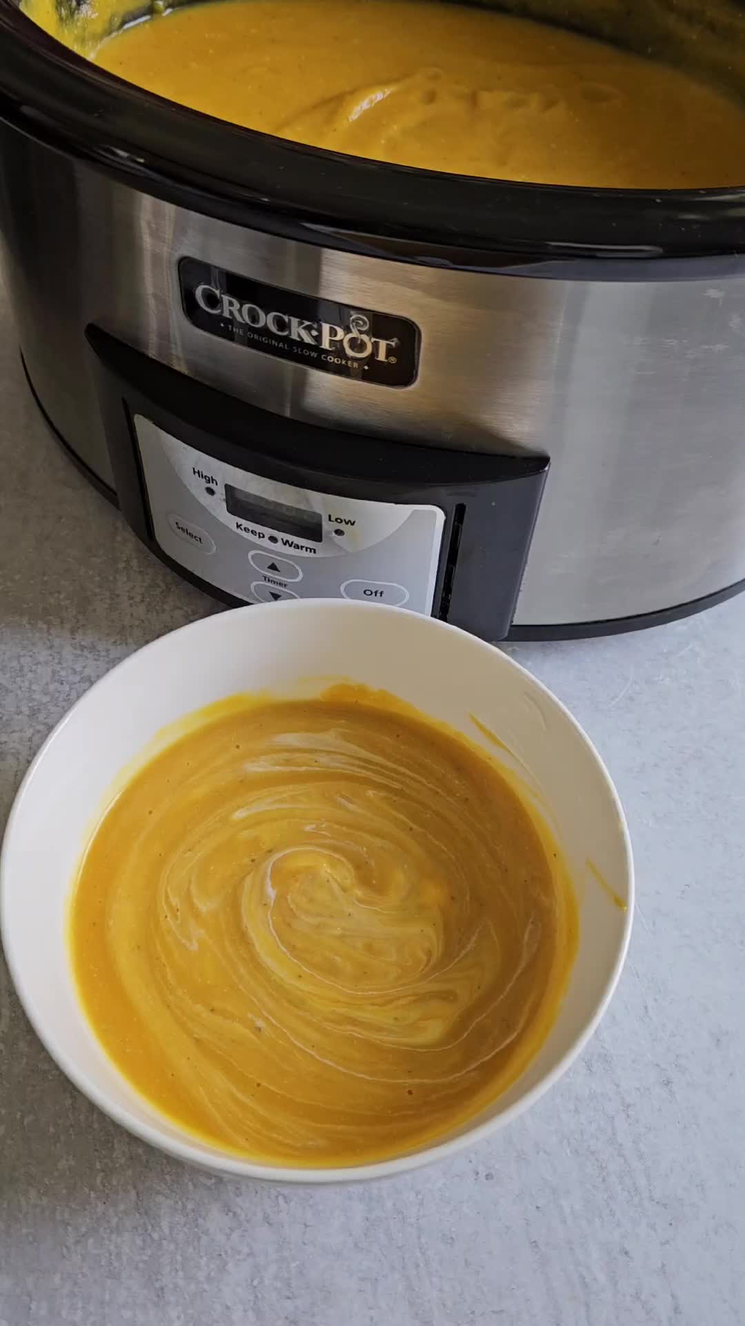 This may contain: a person spooning into a bowl of soup in front of an instant pot with the lid open