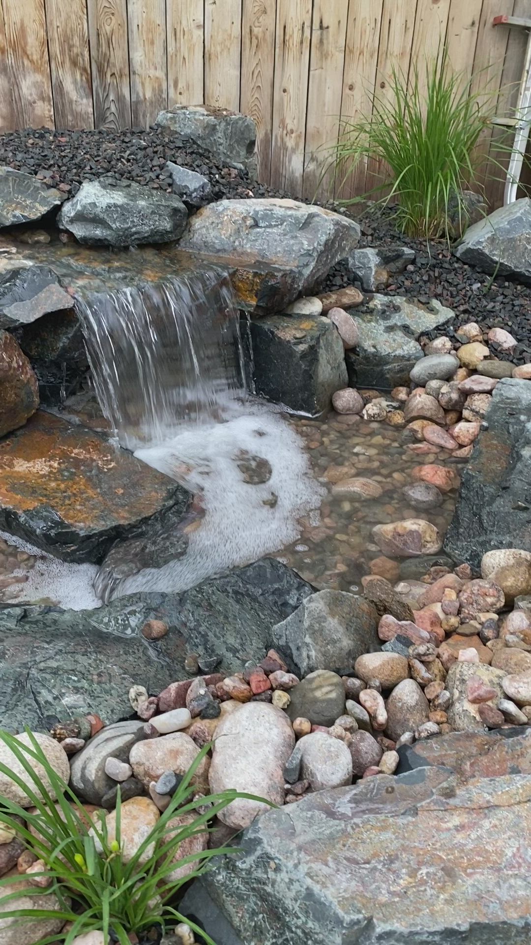 This may contain: there is a small waterfall in the rock garden