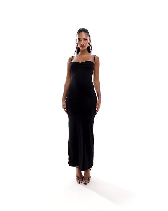 This may contain: a woman in a black dress is standing on a white background and looking at the camera