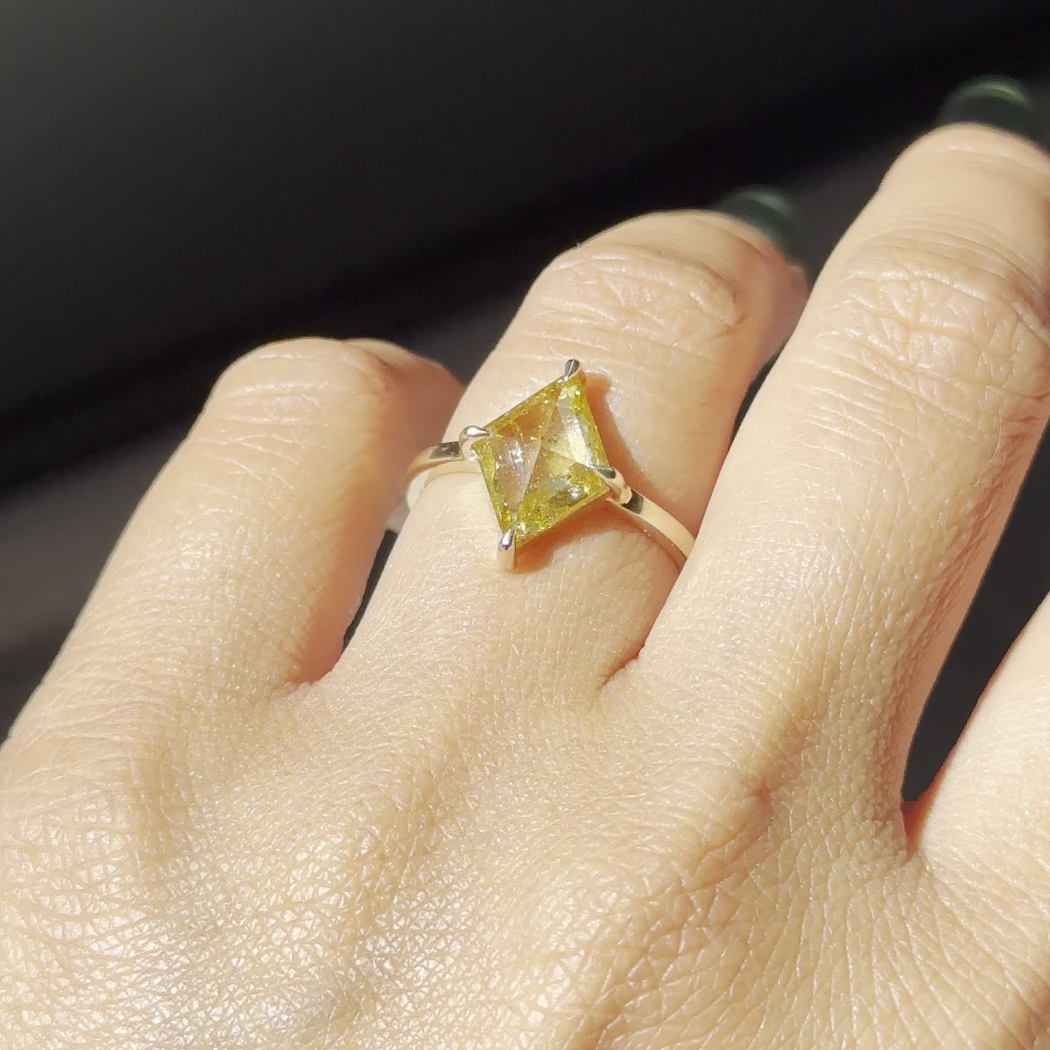 This may contain: a woman's hand with a yellow diamond ring on it