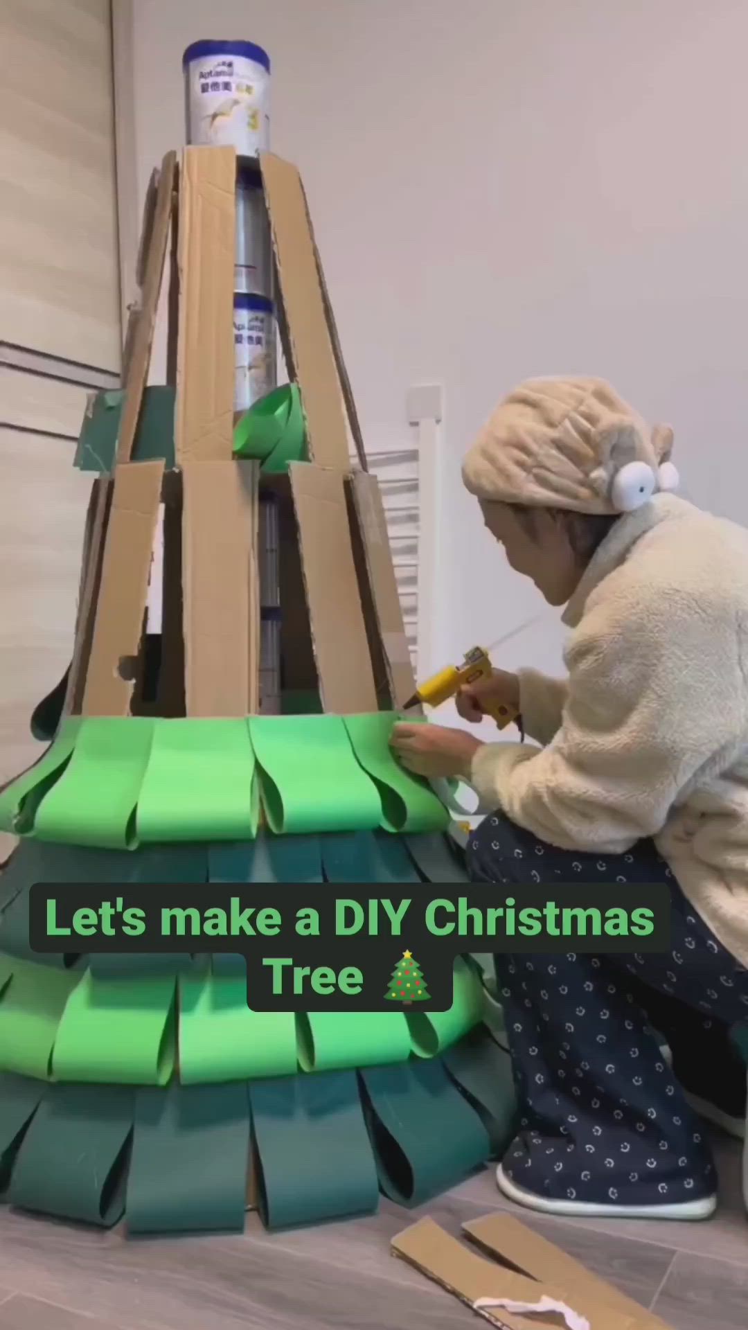 This may contain: a woman is making a diy christmas tree out of cardboard