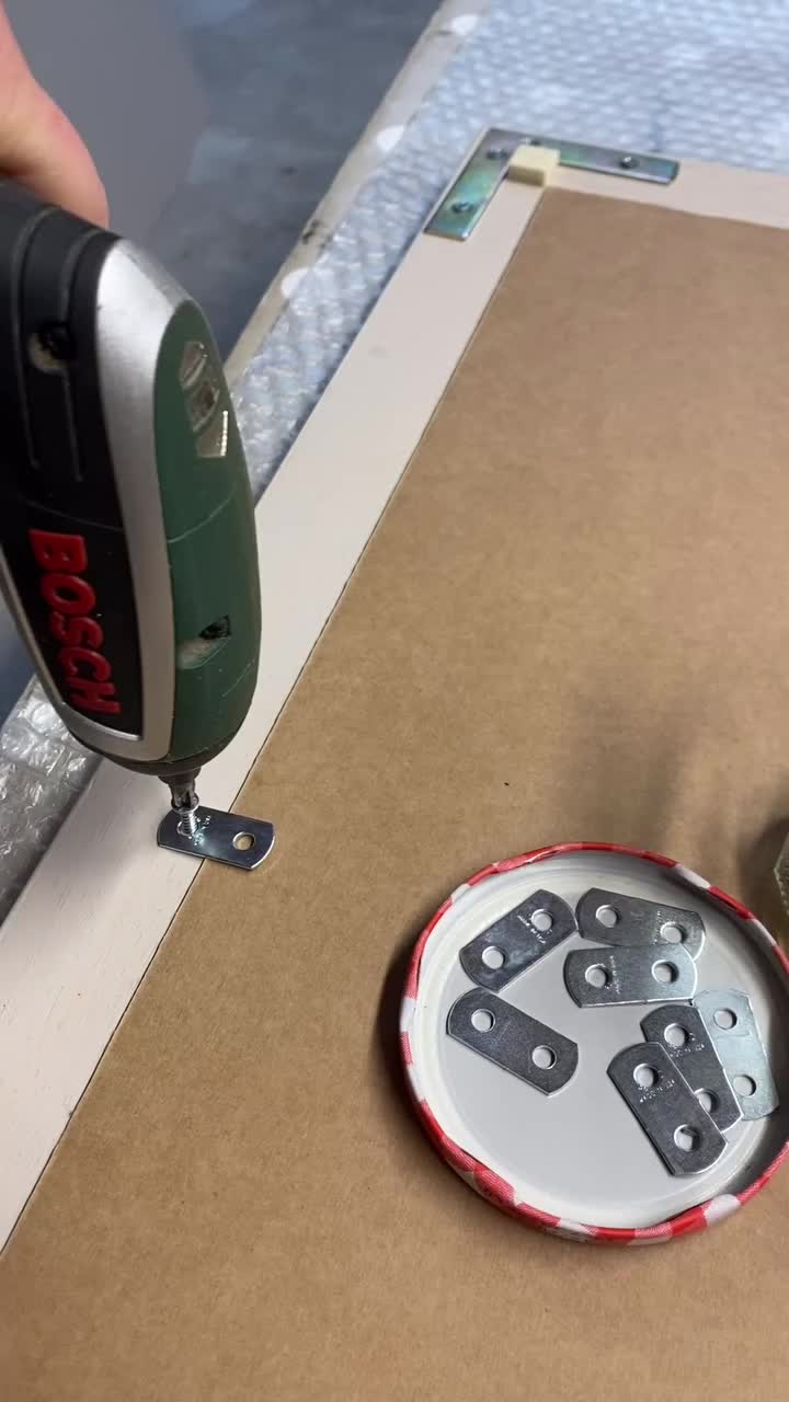 This may contain: a person using a stapler to cut holes in cardboard