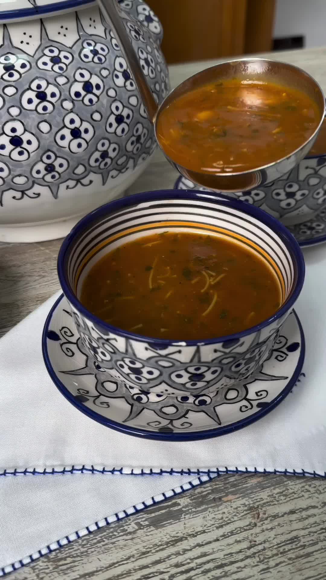 This may contain: a bowl of soup is sitting on a table next to two bowls with spoons