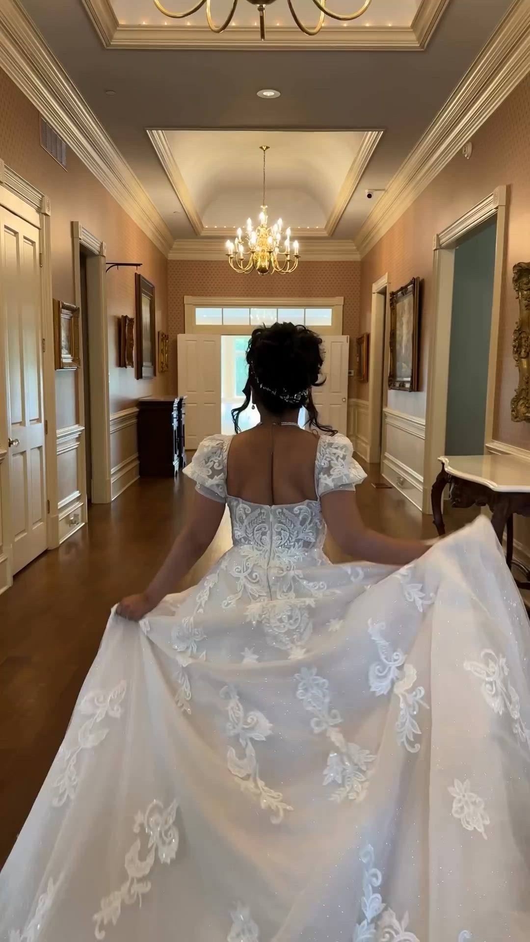 This may contain: a woman in a wedding dress is walking down the hall with her back to the camera