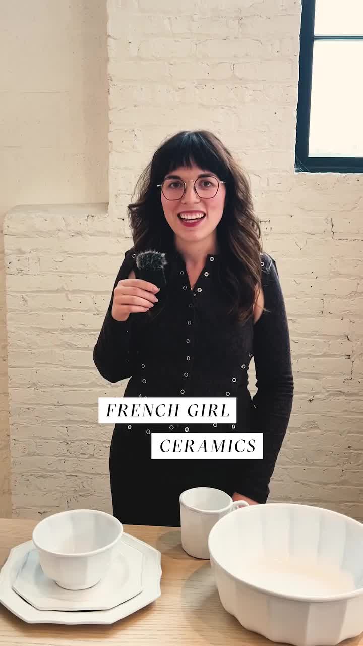 This may contain: a woman standing in front of a table holding a sign that says french girl ceramics