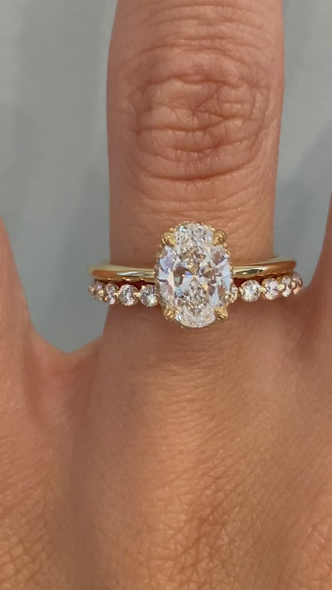 This may contain: a woman's hand with a diamond ring on top of her finger and an engagement band