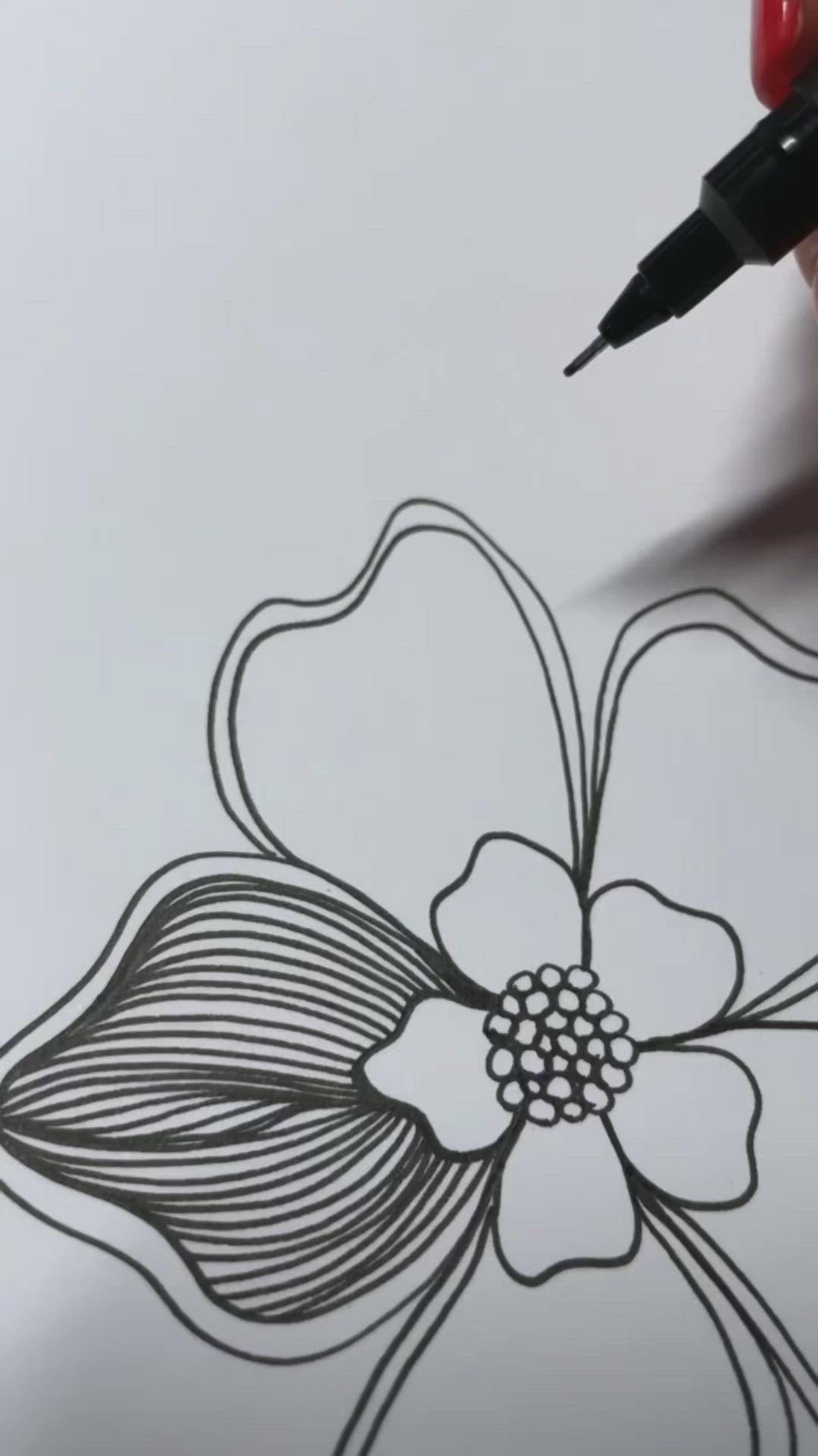 This may contain: a woman's hand holding a pen and drawing a flower