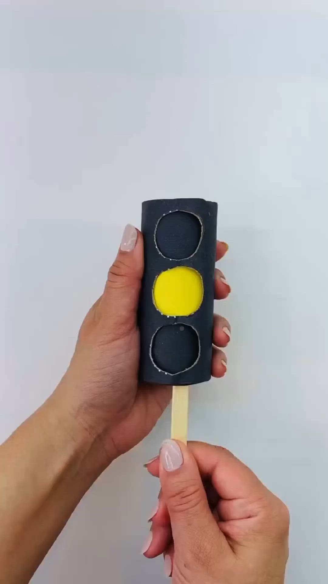 This may contain: a hand holding a black and yellow traffic light lollipop