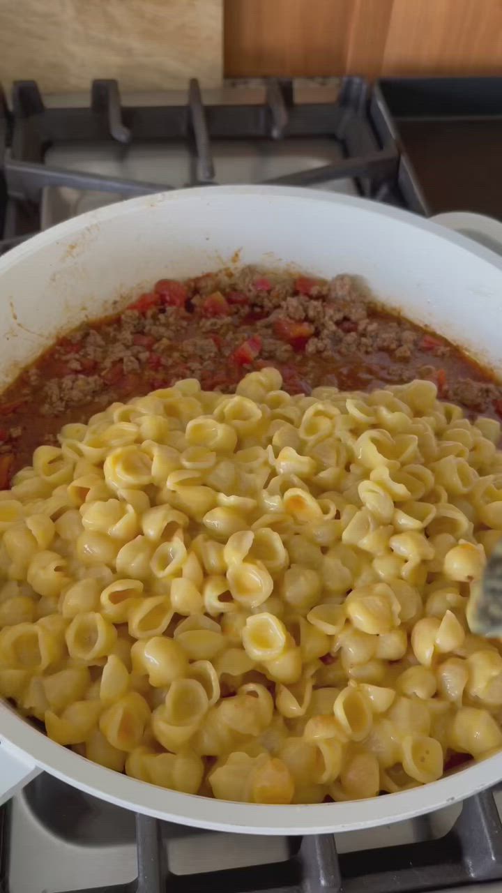 This may contain: a pot filled with pasta and meat on top of a stove