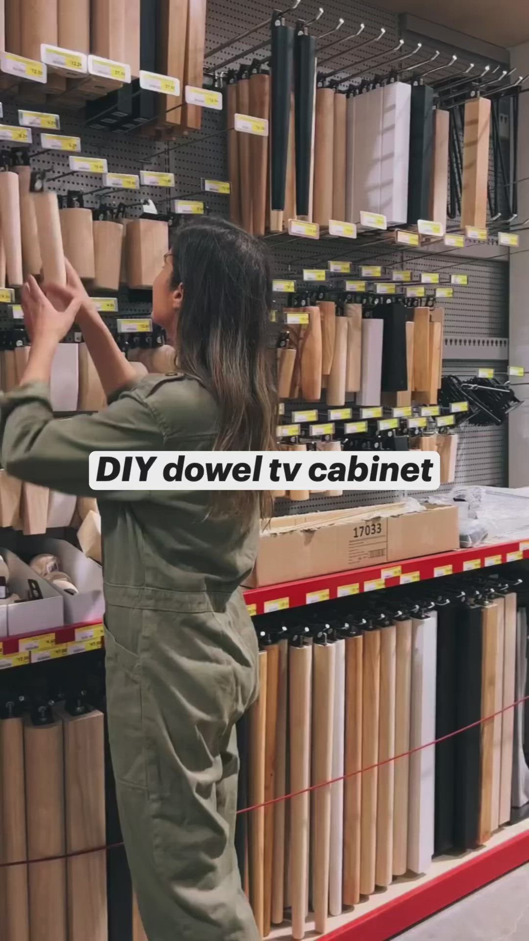 This may contain: a woman in overalls is looking at the shelves with various items on it and text that reads diy dowel tv cabinet