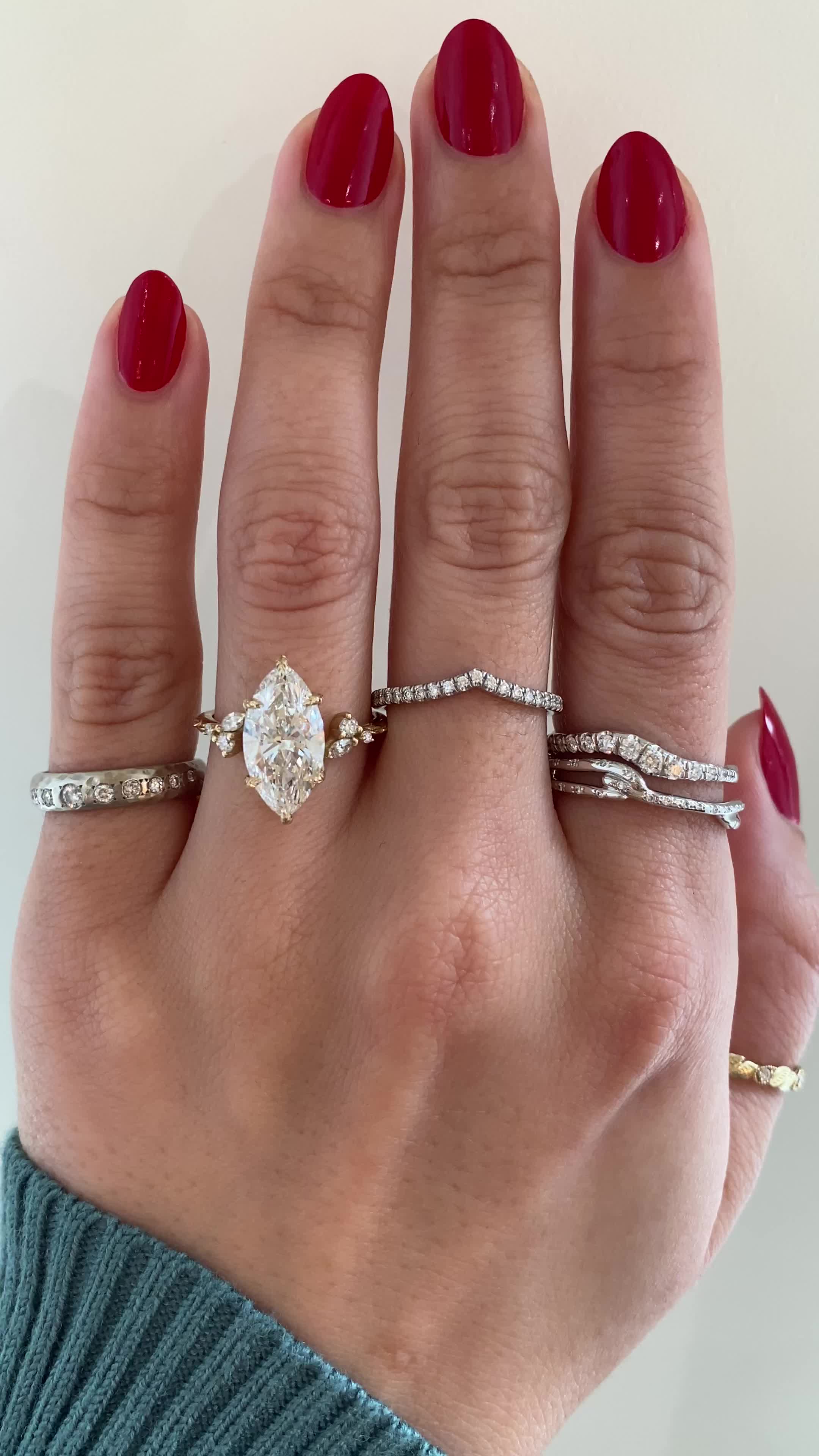 This may contain: a woman's hand with three different rings on her fingers and one is wearing a ring