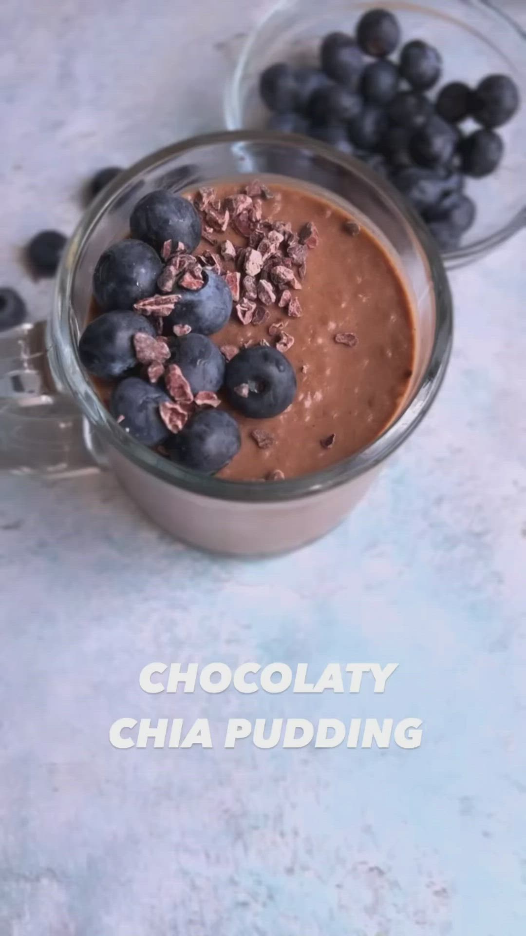 This may contain: chocolate chia pudding with blueberries and granola in a glass bowl on a table