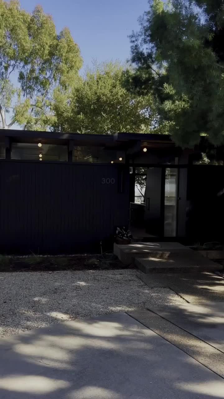 This may contain: a living room with large glass doors that look out onto the outdoors and trees in the distance