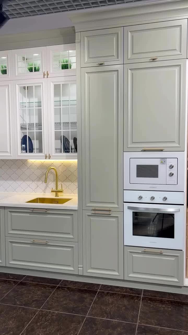 This may contain: a kitchen with white cabinets and gold faucet in the center, an oven built into the wall