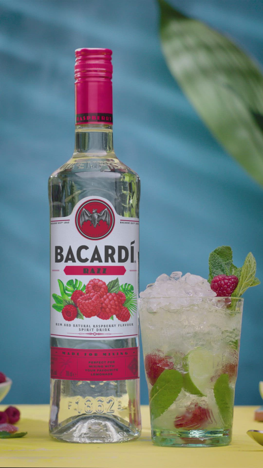 This contains: Das Video zeigt die Zubereitung eines Bacardi Razz Mojitos. Drücke Limettensaft in ein Glas. Vermische dieses mit Zucker. Füge Minzblätter, Himbeeren und Crushed Ice hinzu. 40ml Bacardi Razz darüber gießen, mit Soda Wasser auffüllen, umrühren und genießen.