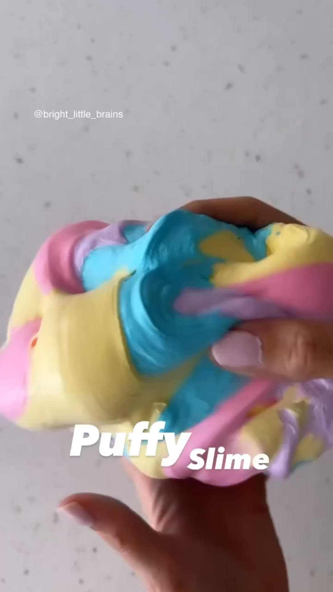 This may contain: a hand holding a doughnut with different colored icing