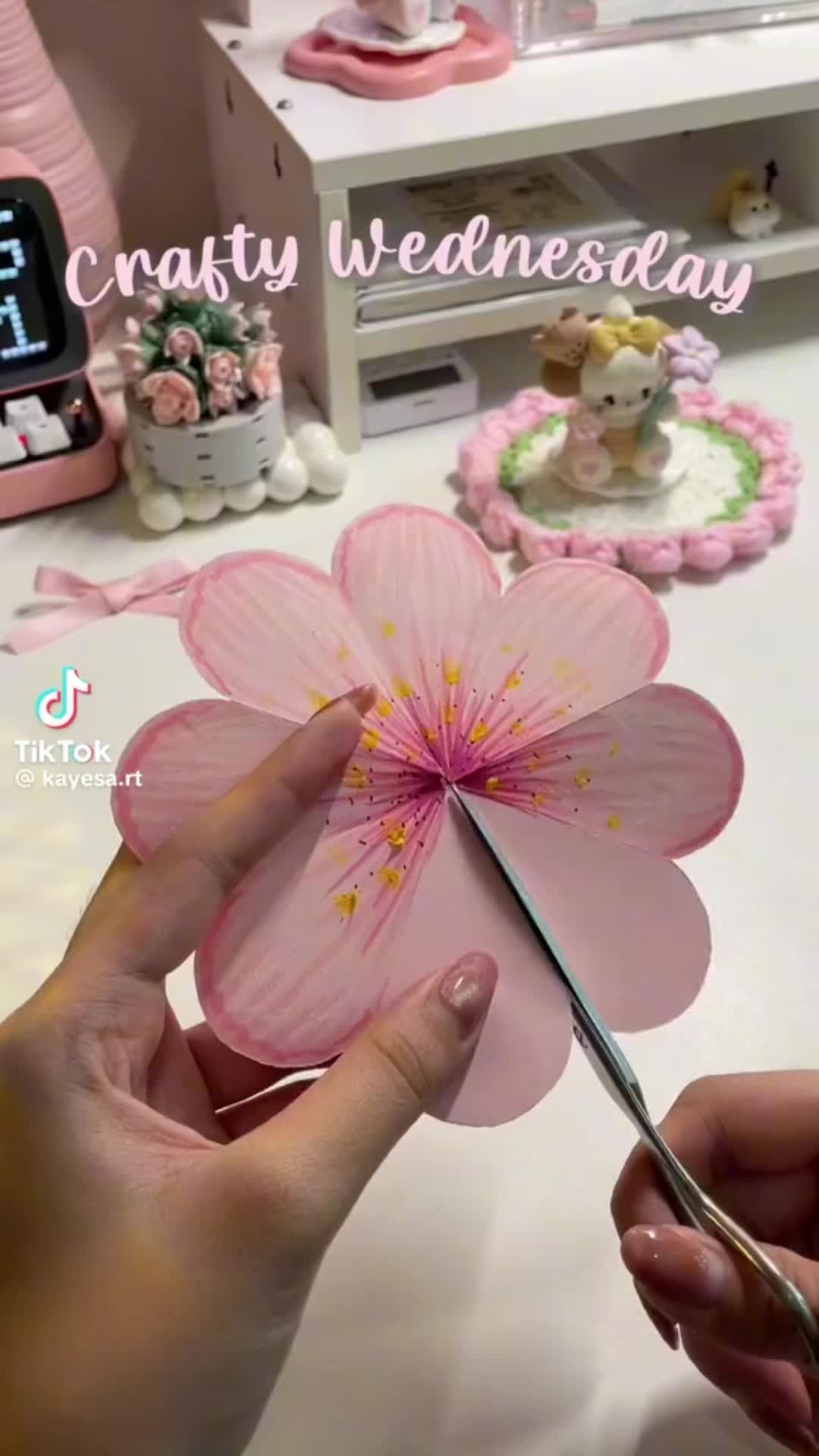 This may contain: a person cutting paper flowers with scissors on a table in front of a clock and other decorations