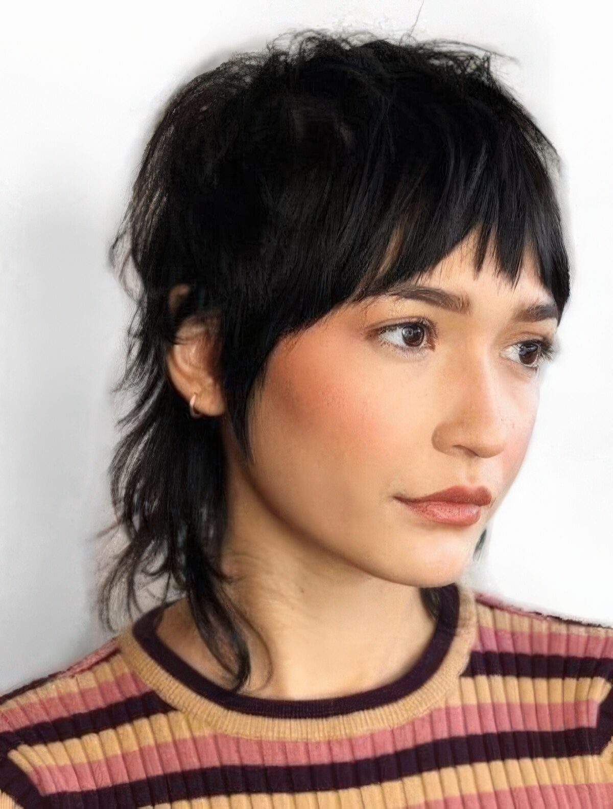 A short black mullet with bangs and shaggy touches is a cool idea that feels and looks very retro-like.