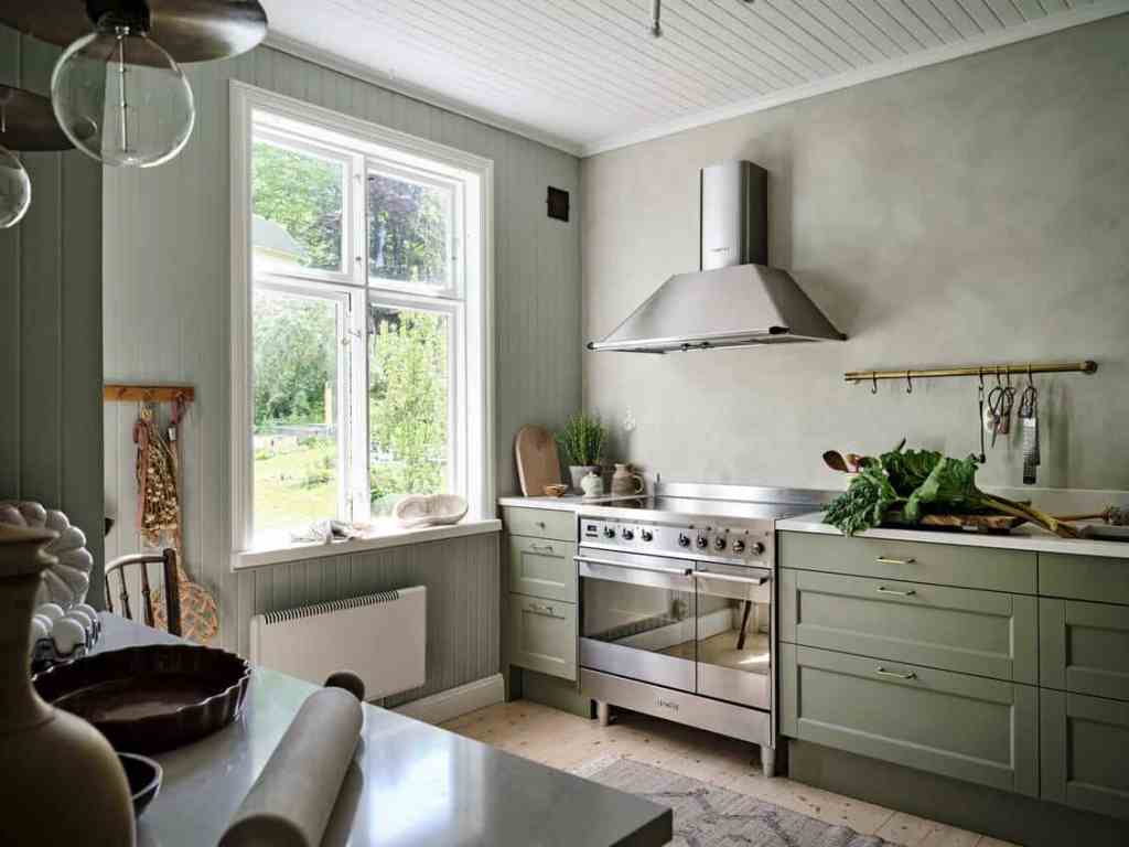 A sage green farmhouse kitchen with sage green limewash paint on the wall