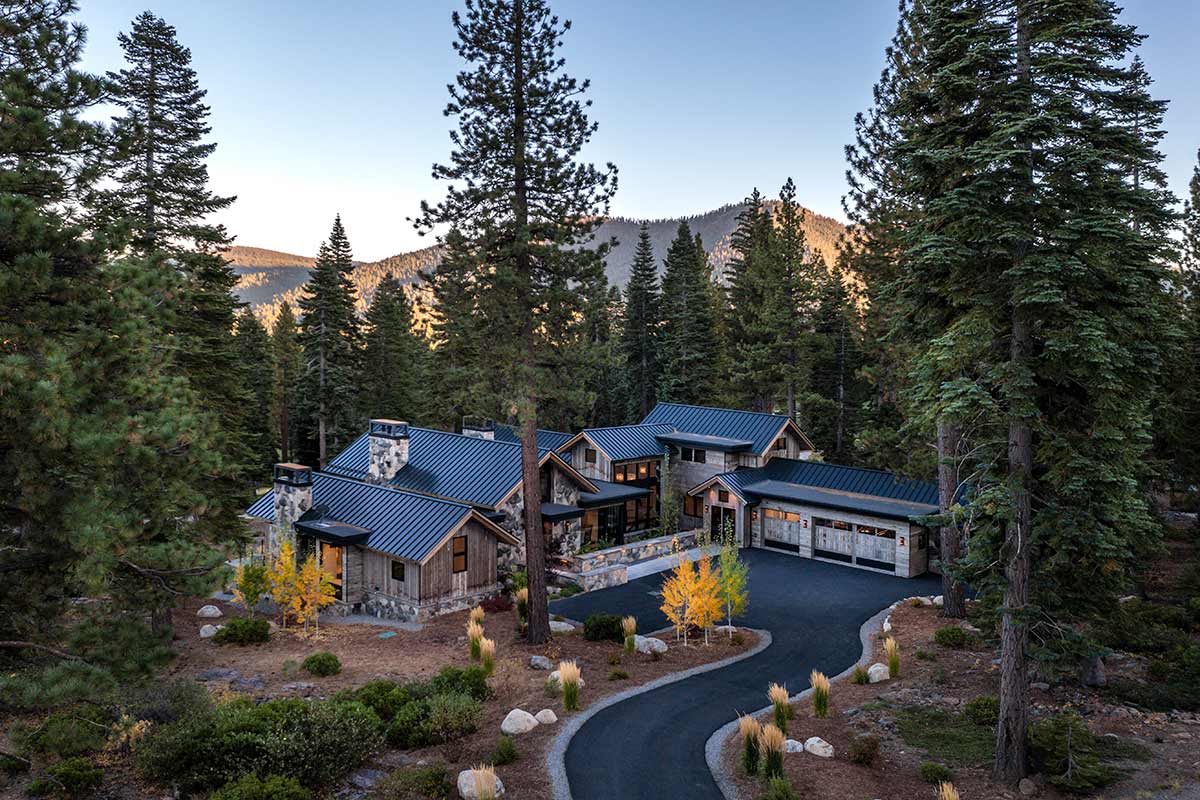 Luxury mountain modern house nestled in a grove of pine trees with a scenic mountain view in the background.