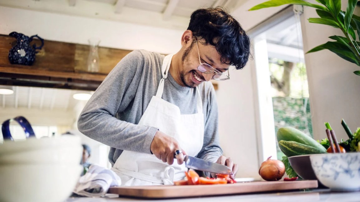 A man cutting food on a cutting board. 