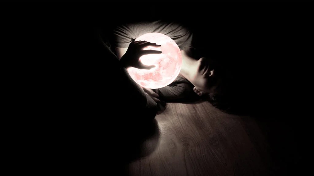 A person lying on the floor while holding an illuminated ball