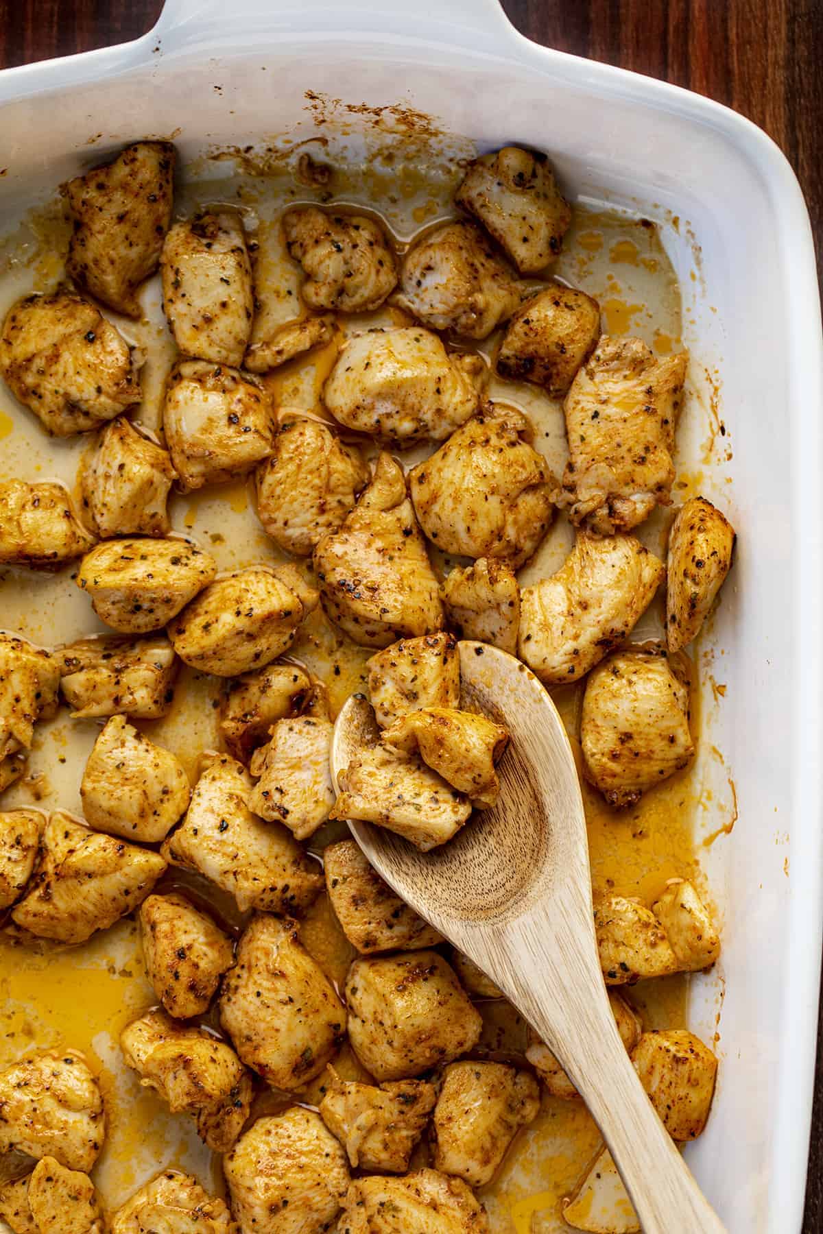 Oven Baked Chicken Bites in Pan with Wooden Spoon.