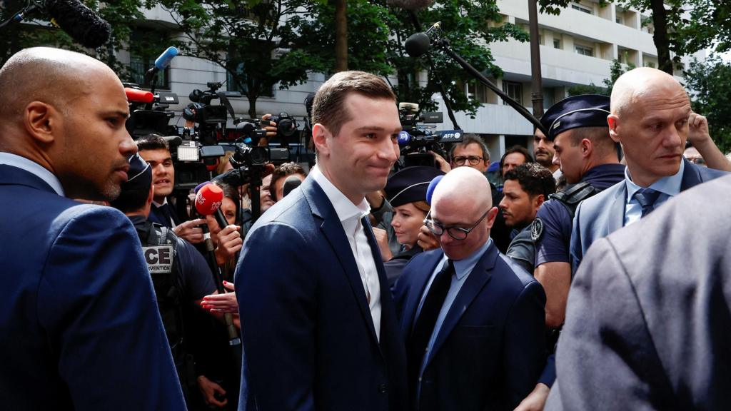 Jordan Bardella arrives at the RN party headquarters surrounded by media