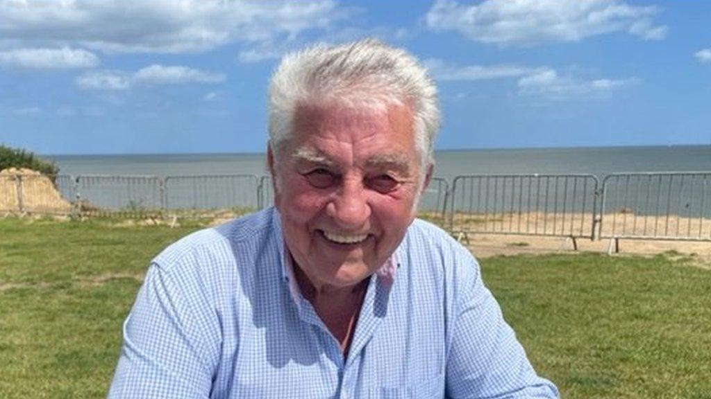 Portrait of man sitting with sea in background.