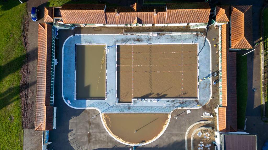 A swimming pool seen from above full of brown water