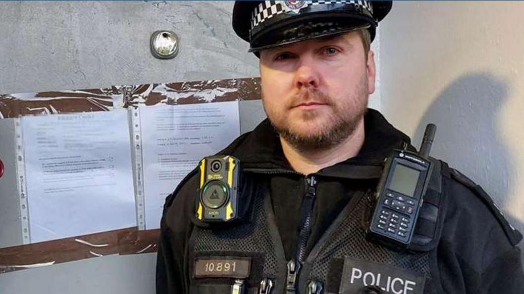 Close up shot of Sergeant Steve Cole in police uniform next to door in Northfleet with closure notice posted on it