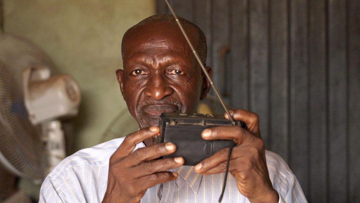 Bala Muhammad holding a radio in his shop