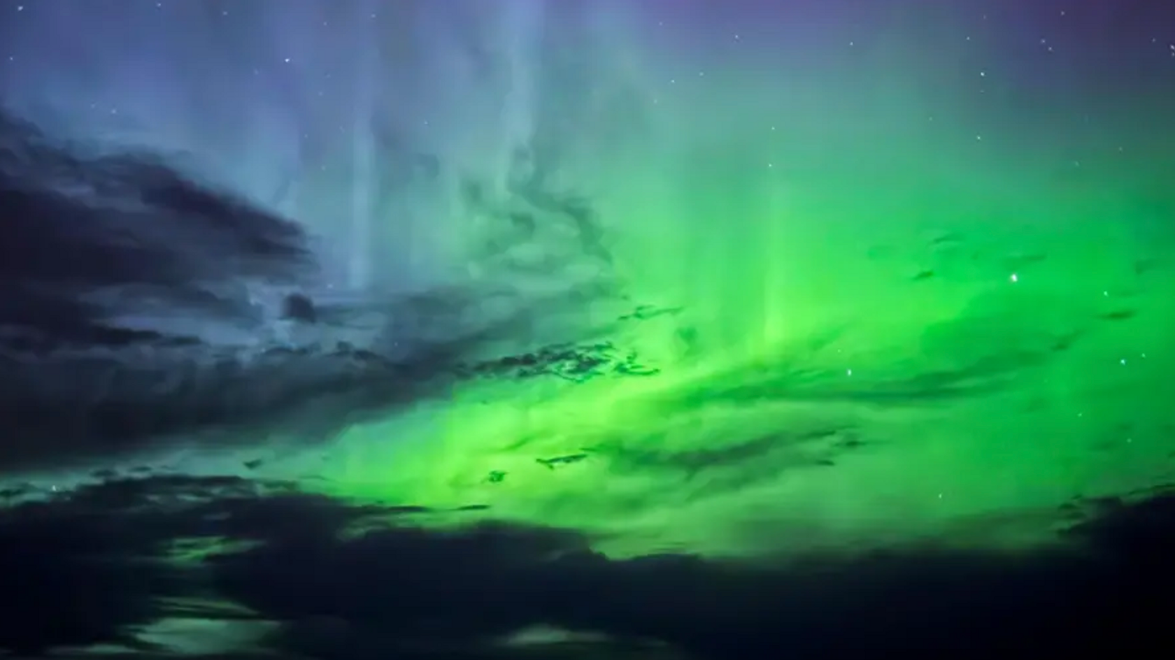 Sky filled with greens and and darker clouds during an aurora display