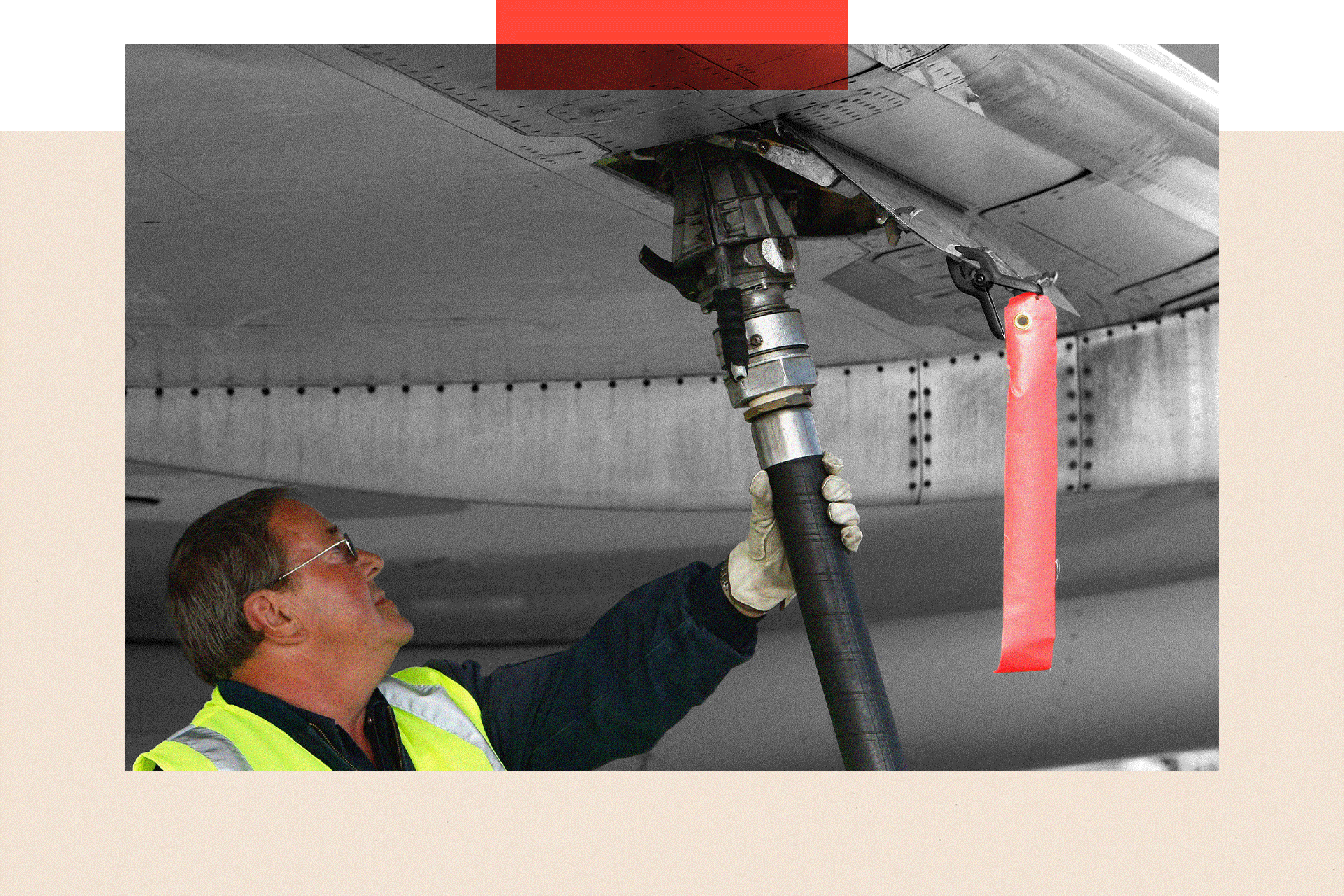 A man in hi-vis vest monitors a fuelling hose while refuelling an American Airlines plane. 