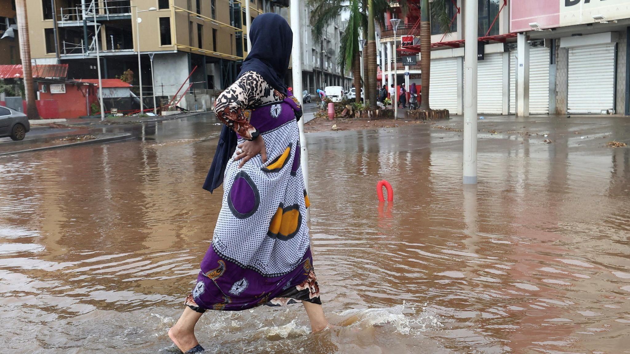 A person walks in a flooded street after heavy rains in the aftermath of Cyclone Chido, in Mamoudzou, Mayotte, France, 19 December 2024