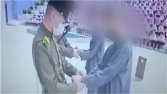 North Korean soldiers handcuffing two teenagers