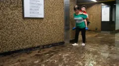 9 月 8 日，香港黃大仙地鐵站發生嚴重水災，一名兒童被背過泥濘的地面。