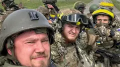 Members of Russian Volunteer Corps pose for a picture atop an armoured vehicle at Graivoron border crossing in Kozinka, Belgorod region, Russia, in this handout picture released on May 23, 2023