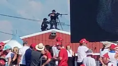 A Secret Service agent on a rooftop at a Donald Trump rally