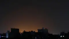 也門薩那在周六遭受美軍空襲後，一處街區建築物後面被爆炸的火光照亮。