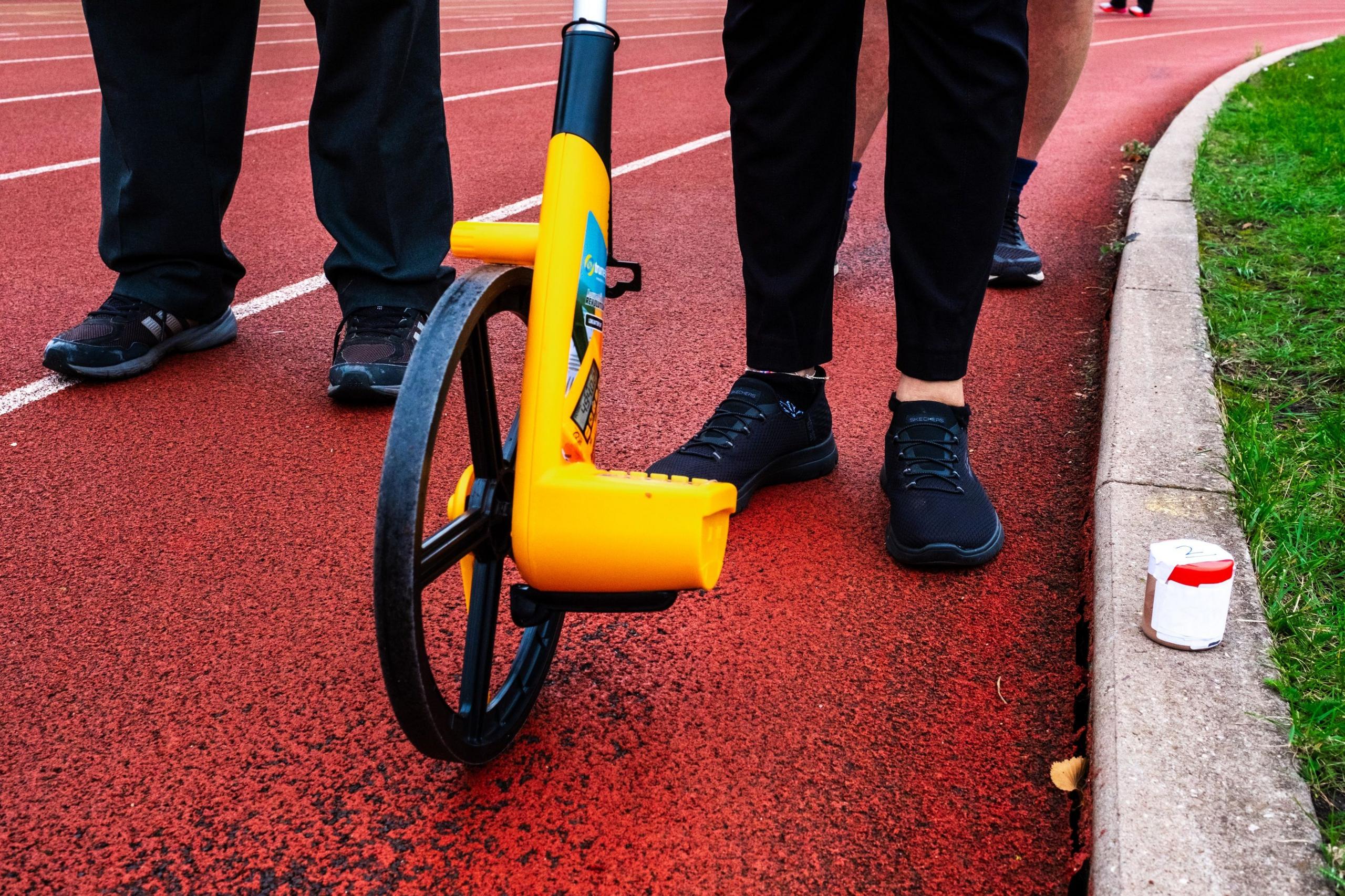 Officials measure a runners' completed distance at the Sri Chinmoy 24hr Track Race